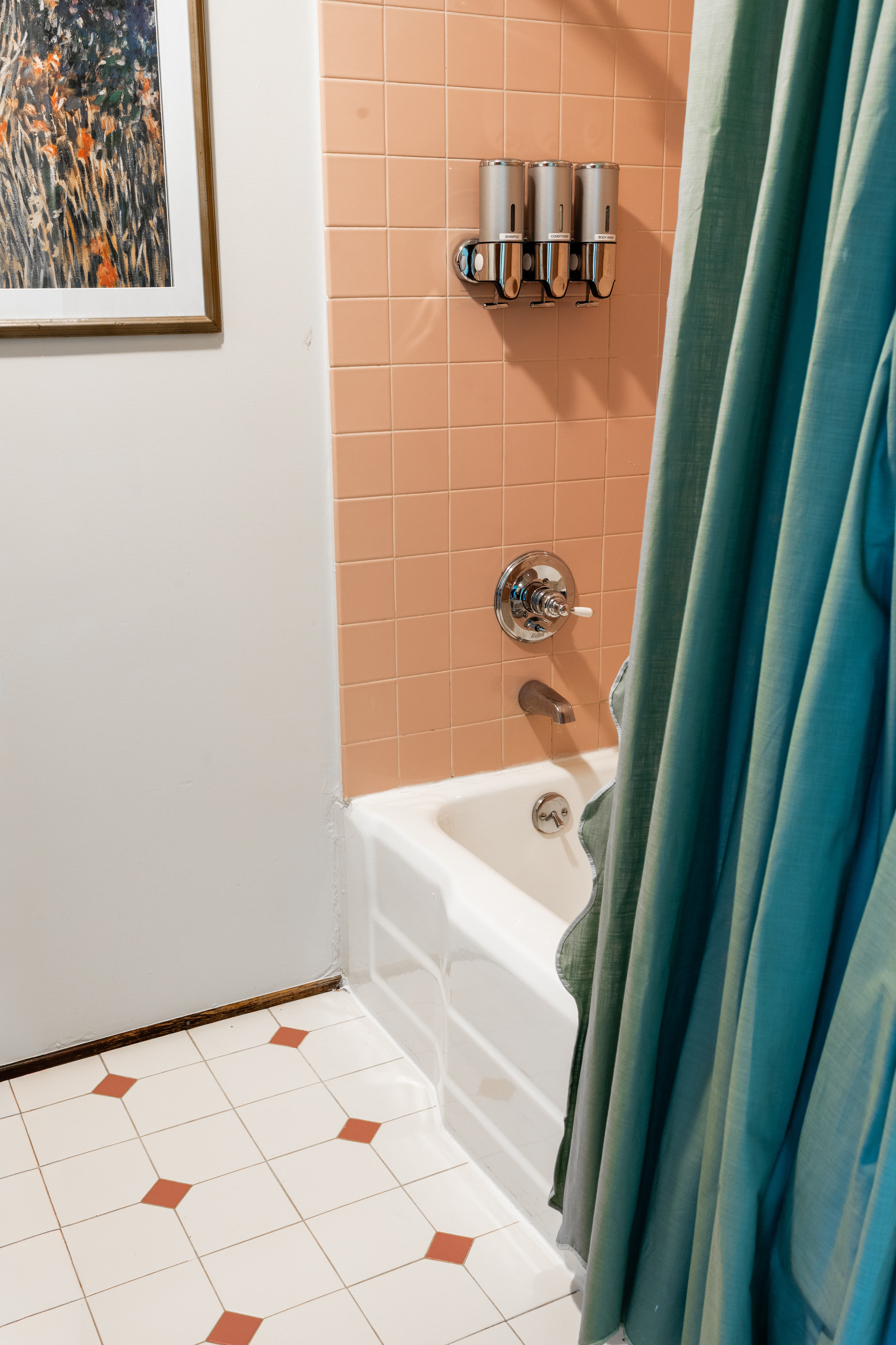 A bathroom corner featuring a bathtub, a shower curtain, and pink tiled walls.
