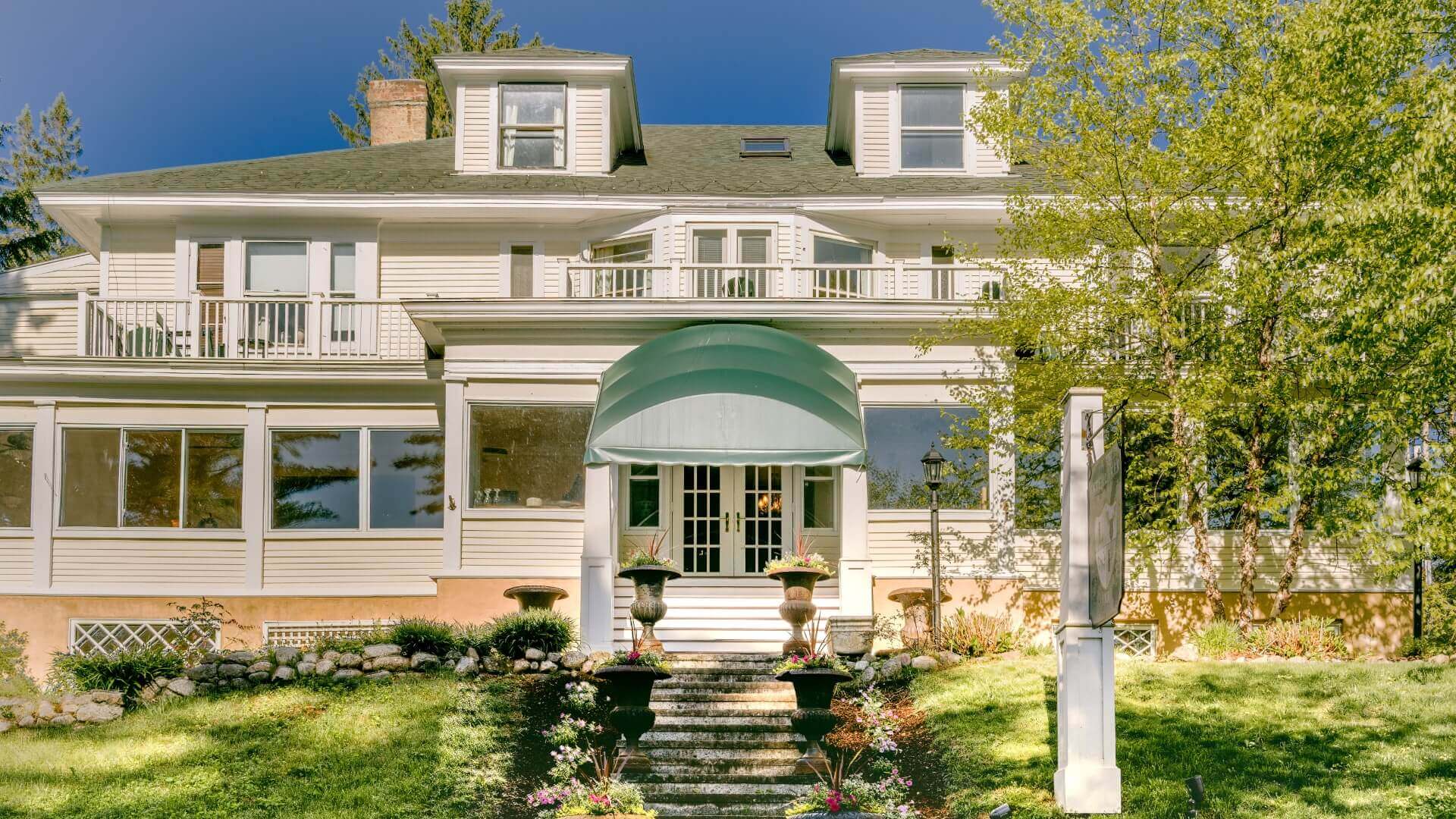 A large, elegant house with a green awning and landscaped front yard.