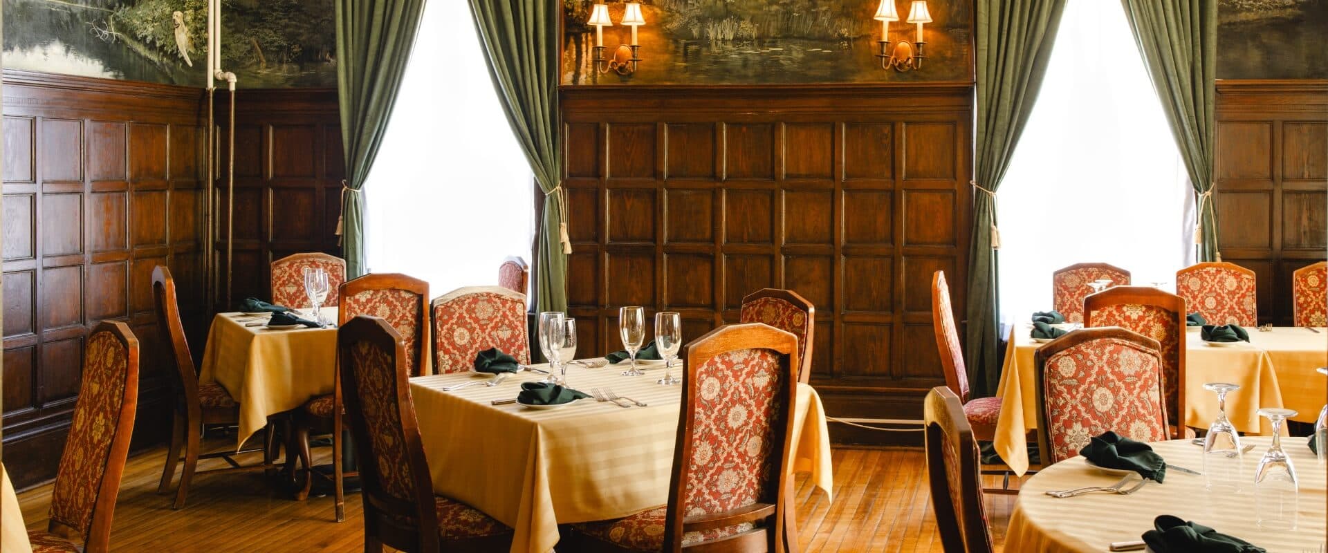 Elegant restaurant interior featuring wooden walls, patterned chairs, and neatly set tables.