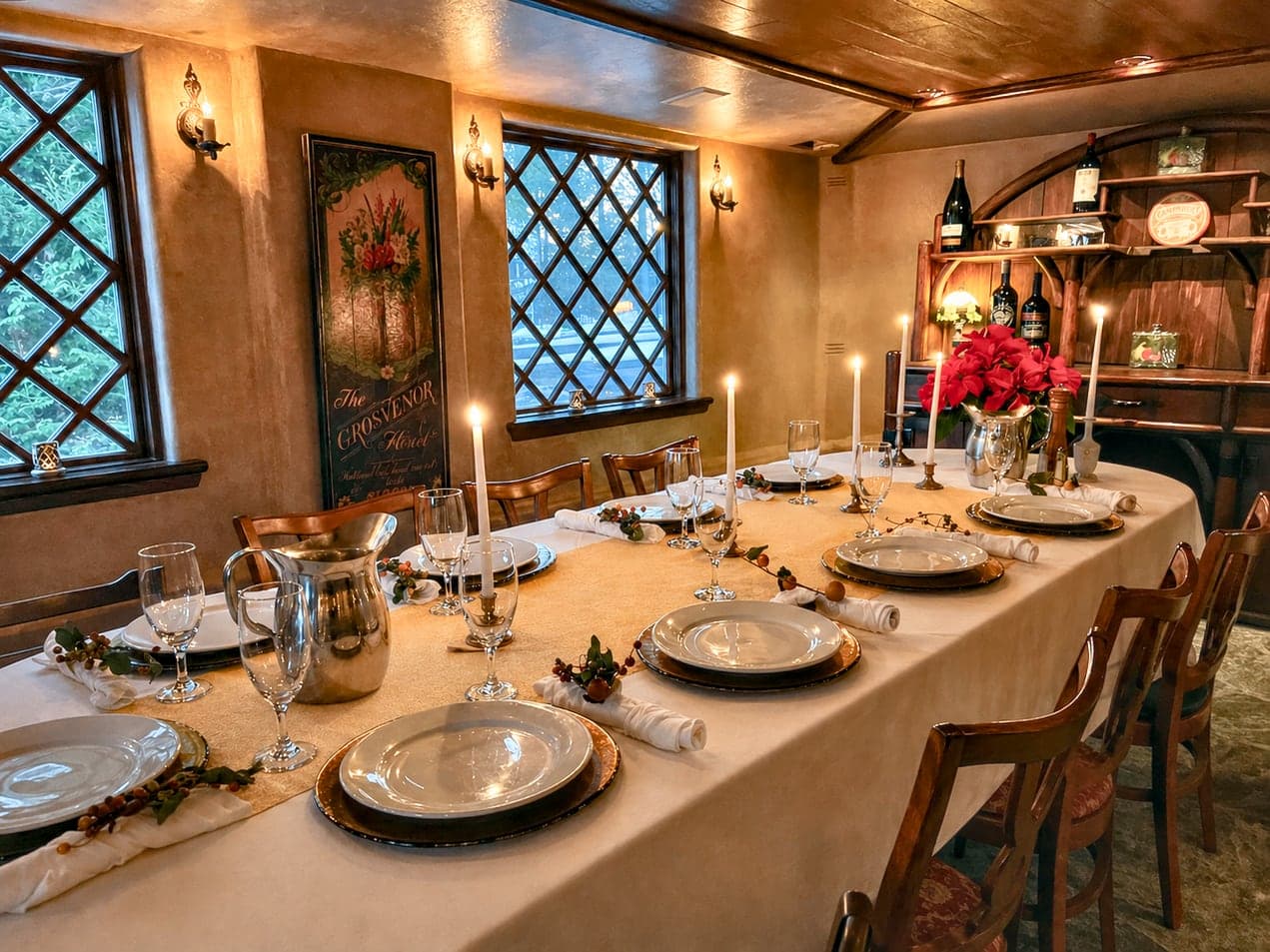 A beautifully set dining table with candles, elegant dishes, and decorative flowers in a warmly lit room.