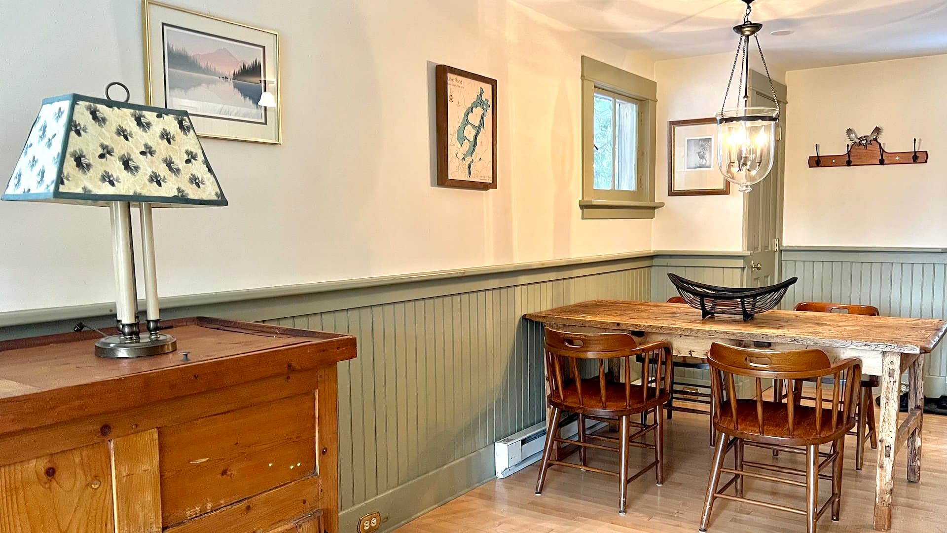 A cozy dining area featuring a wooden table, chairs, and soft lighting from a lamp.