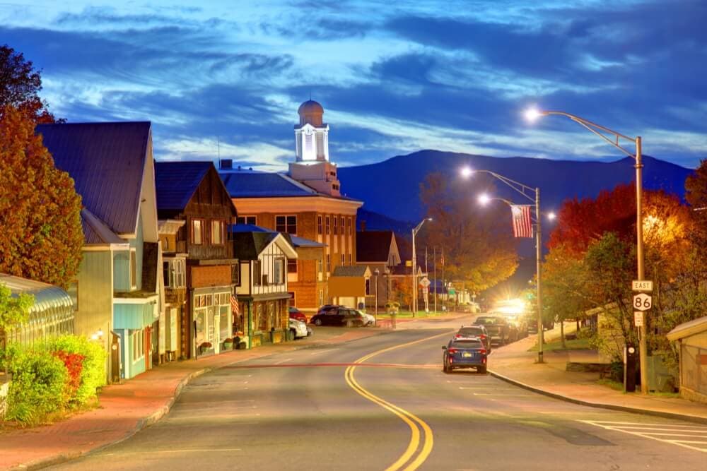A quiet street lined with quaint shops and a clock tower under a twilight sky.
