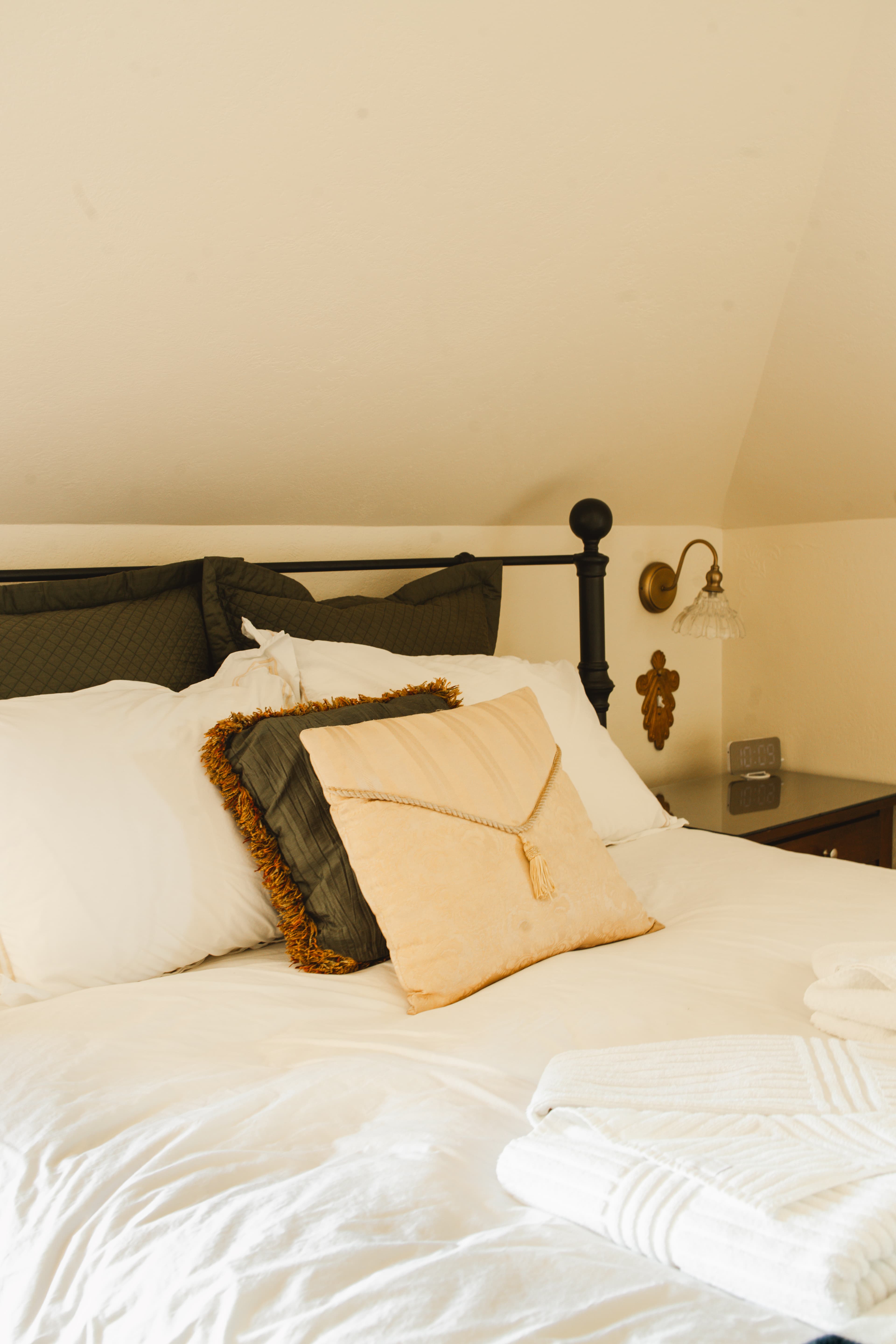 A neatly made bed with decorative pillows and a bedside lamp in a cozy room.