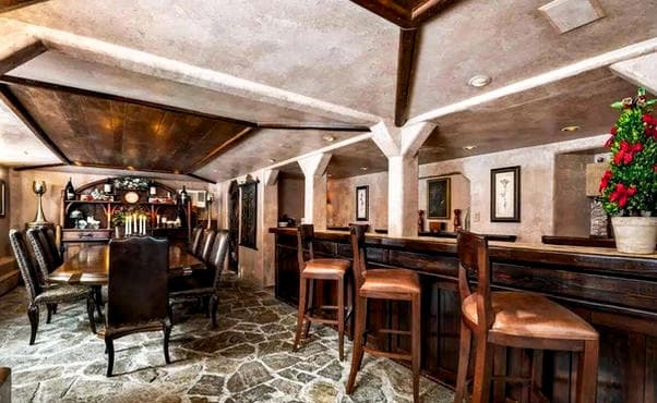 A rustic bar and dining area featuring wooden furniture and stone flooring.