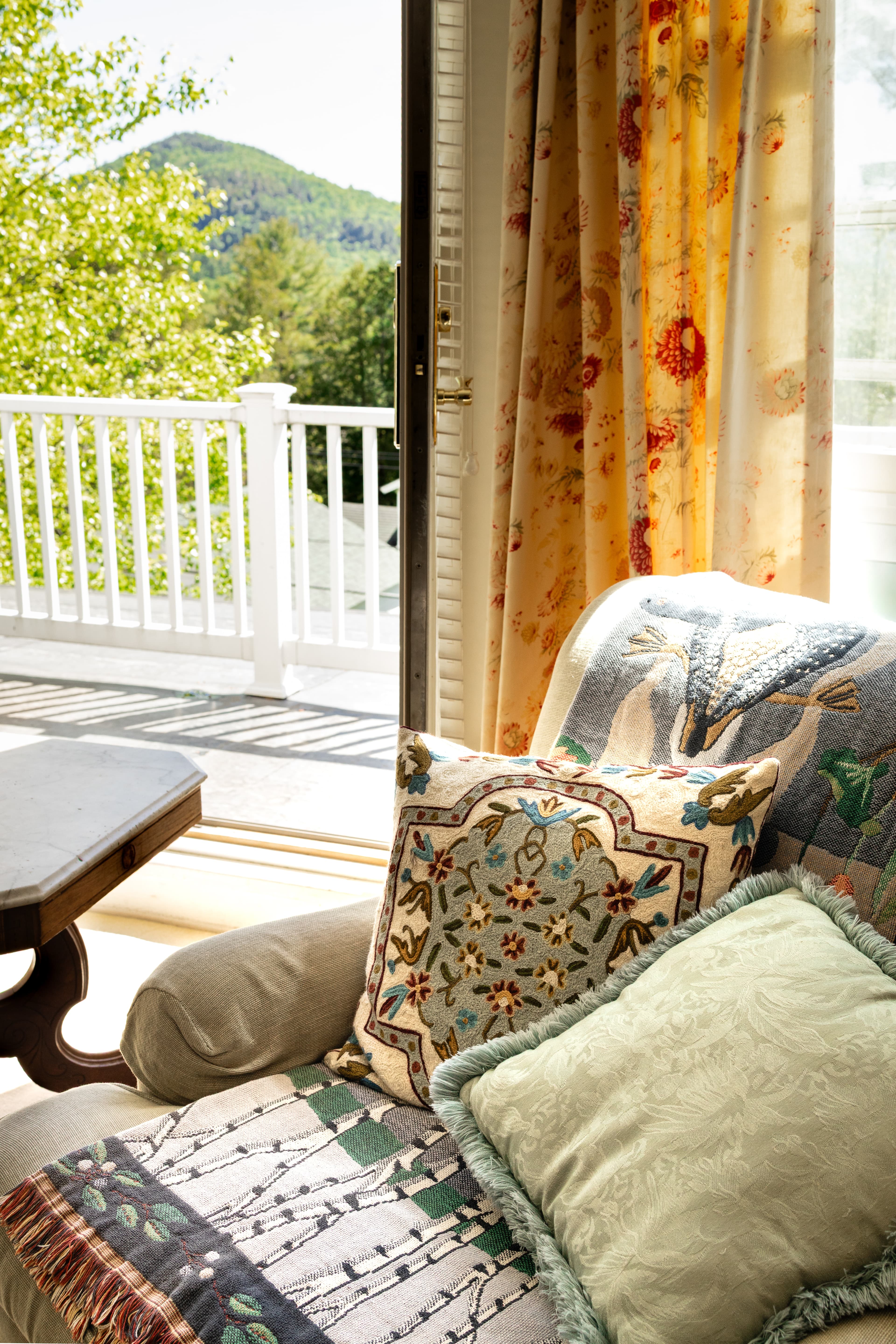 A cozy seating area with decorative pillows and curtains, overlooking a scenic view.